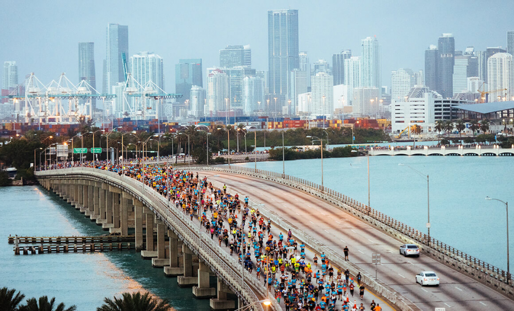 Milhares de corredores na MacArthur Causeway com o skyline de Miami ao fundo durante a Maratona de Miami